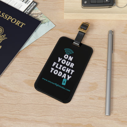 OYFT Luggage tag with buckle strap on a desk next to a pen and passport. 
