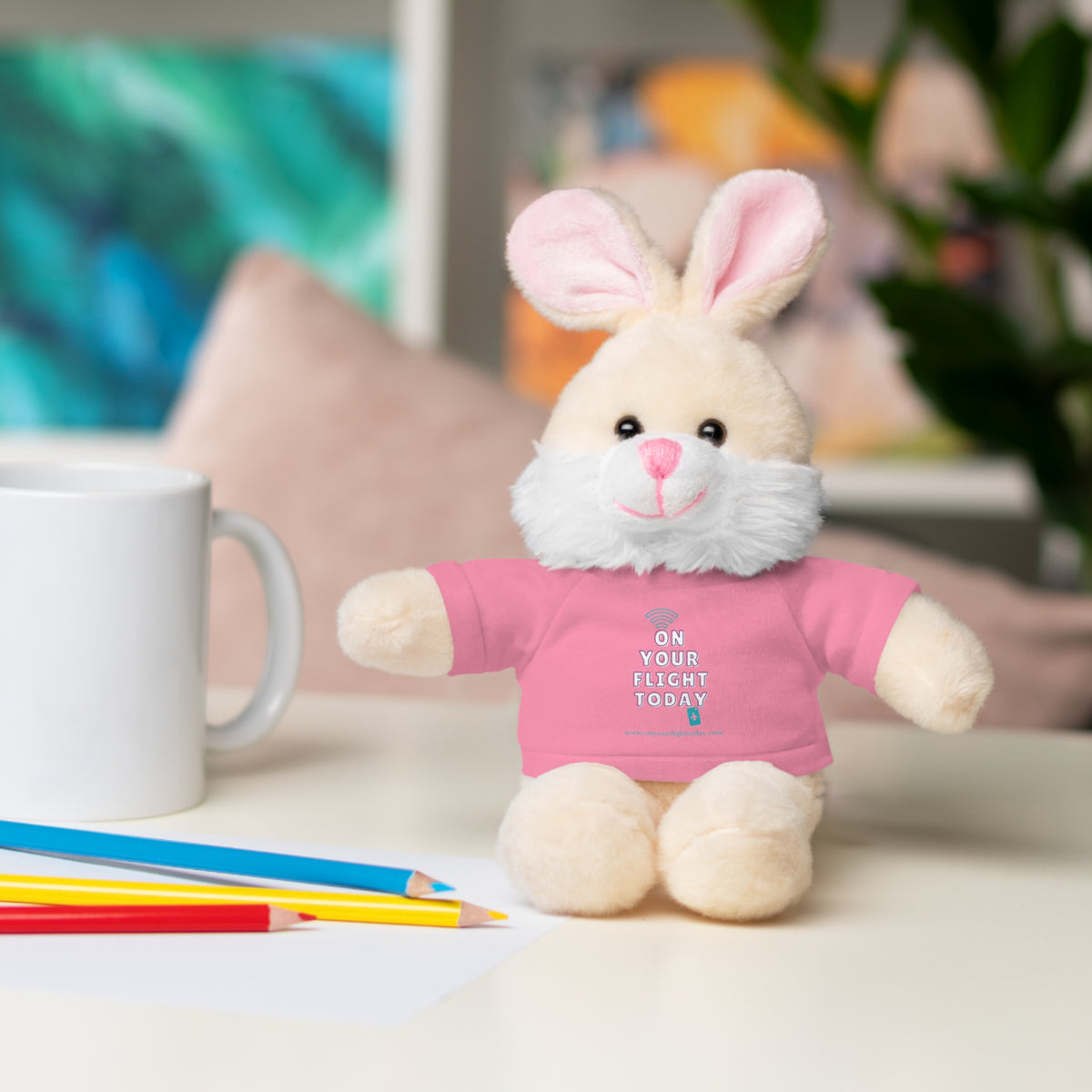 Bunny in pink OYFT tee next to a mug. 