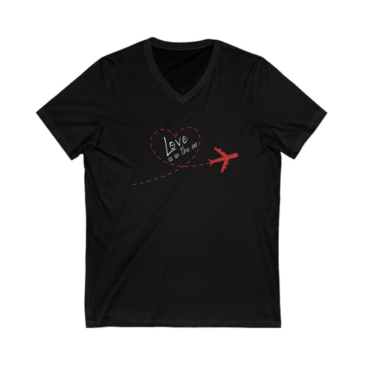 Black tee with red plain that has a trail that forms the shape of a heart. Within the heart is the text 'Love is in the air'. 