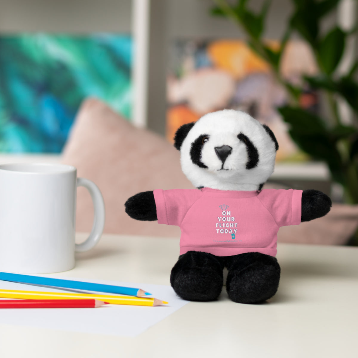Panda bear in pink OYFT tee next to a mug.